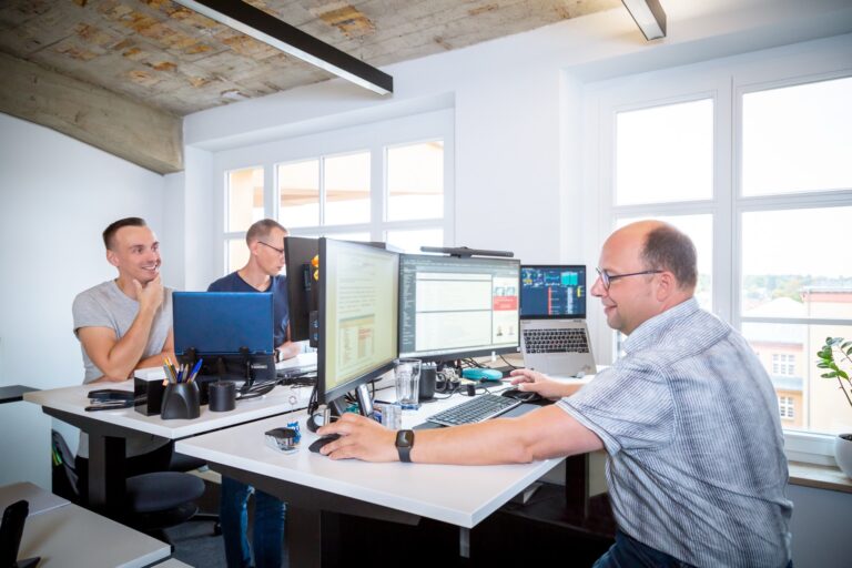 zwei Mitarbeiter in Büro vor Bildschirm